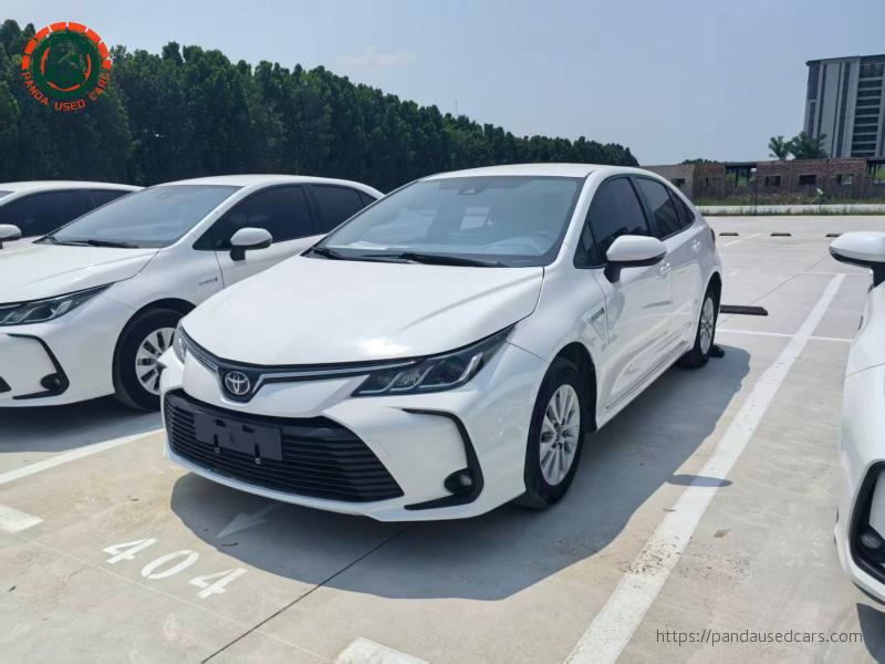 Front three-quarter view of a white Toyota Corolla Hybrid sedan in a vehicle yard