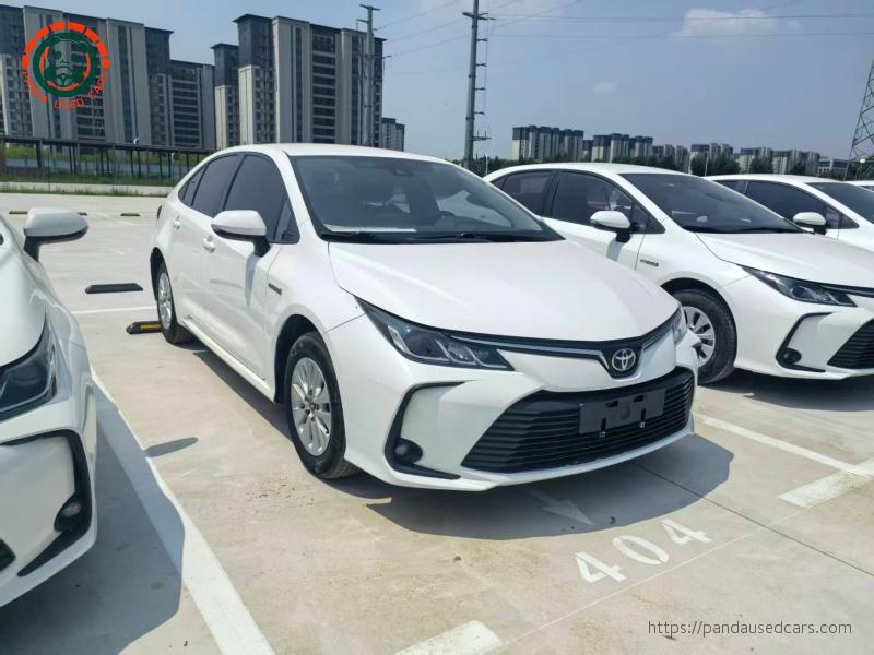 Alternative front three-quarter view of a white Toyota Corolla Hybrid sedan in a vehicle yard